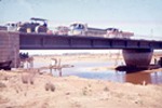 Vista paso de camiones y maquinaria sobre el puente en construcción